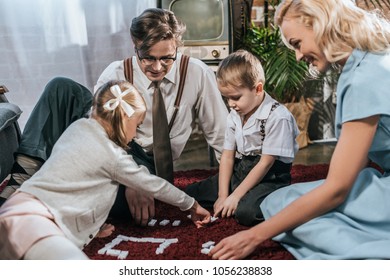 smiling old-fashioned family playing dominoes together at home 