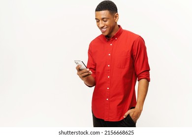 Smiling optimistic African-American young man in red casual shirt using smartphone isolated on white, multiracial freelancer or student gay chatting online, texting, messaging, web surfing, copy space - Powered by Shutterstock