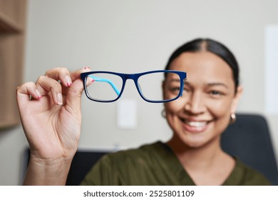 Smiling Optometrist Holding Stylish Blue Eyeglasses in Professional Office Setting - Powered by Shutterstock