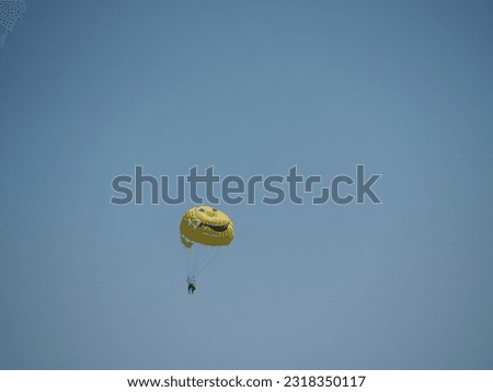 A smiling parachute in the blue sky.  Parasailing activity.