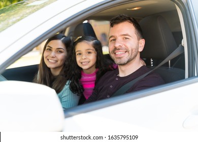Smiling Parents With Daughter Sitting In Car While Making Eye Contact During Weekend