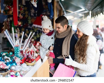 Smiling parents with small daughter at counter of X-mas market