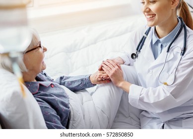 Smiling patient keeping hand of doctor