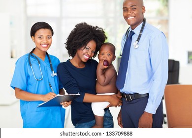 smiling pediatric medical professionals with african mother holding her baby