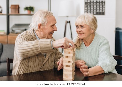 Smiling Pensioners Playing Jenga Game On Table