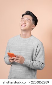 Smiling pensive young man standing looking aside up using mobile cell phone typing sms message isolated  - Shutterstock ID 2236852289