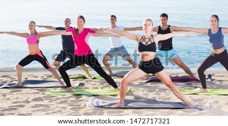 Smiling people doing workout on beach in sunny morning