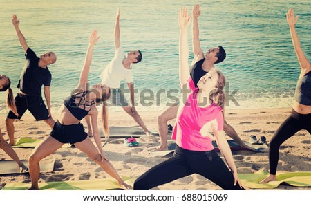 Smiling people doing workout on beach in sunny morning