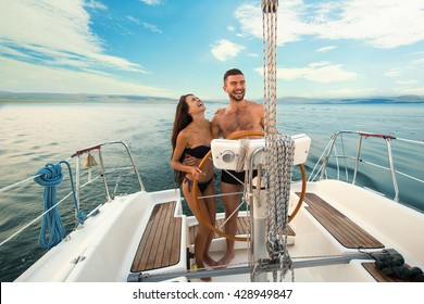 Smiling People At Yacht Wheel. Guy With Girl On Yacht. Another Day In Open Sea. Lots Of New Impressions.