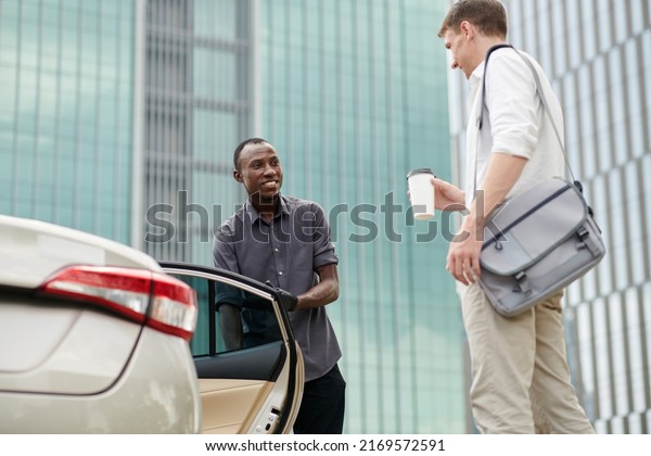 Smiling\
personal driver opening car door for\
passenger
