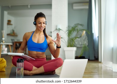 Smiling personal trainer having online consultation with her clients over laptop at home. 