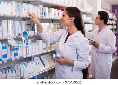 Smiling Pharmacist And Indian Pharmacy Technician Posing In Drugstore