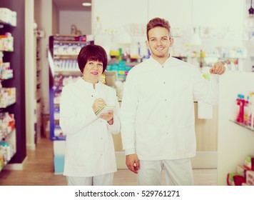 Smiling Pharmacist And Pharmacy Technician Posing In Drugstore