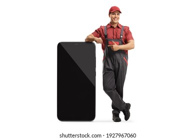 Smiling Phone Repairman Leaning On A Big Smartphone And Pointing Isolated On White Background