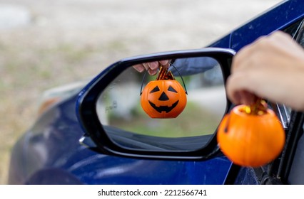 smiling plastic halloween pumpkin mini small pumpkin in reflection rear view retractable lateral mirror.woman hand holding pumpkin bucket handle.trick or treat holiday, car auto vehicle vehicle part - Shutterstock ID 2212566741