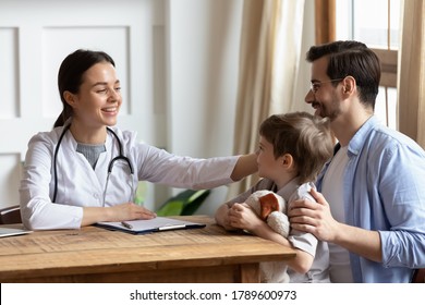 Smiling pleasant young female doctor in medical coat stroking head of little patient, visiting clinic with father. Happy small child boy enjoying pediatrician checkup meeting with daddy in hospital. - Powered by Shutterstock