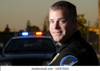 A Smiling Police K9 Officer In Front Of His Patrol Car.