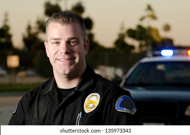 A Smiling Police K9 Officer In Front Of His Patrol Car.