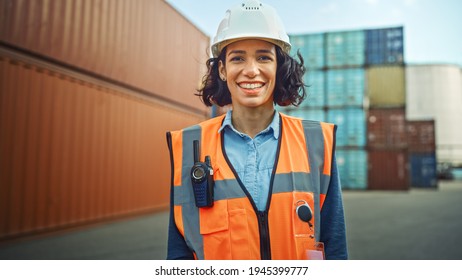 Smiling Portrait of a Beautiful Hispanic Female Industrial Engineer in White Hard Hat, Safety Vest and with Two-Way Radio Working in Logistics Center. Inspector or Supervisor in Container Terminal.