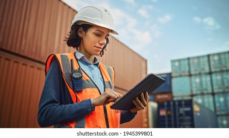 Smiling Portrait of a Beautiful Latin Female Industrial Engineer in White Hard Hat, High-Visibility Vest Working on Tablet Computer. Inspector or Safety Supervisor in Container Terminal. - Powered by Shutterstock