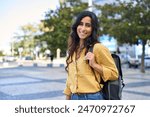 Smiling portrait of beautiful middle eastern Israel girl student with backpack looking at camera at campus city urban background. Young Arabian or Indian woman standing at street outdoor, copy space