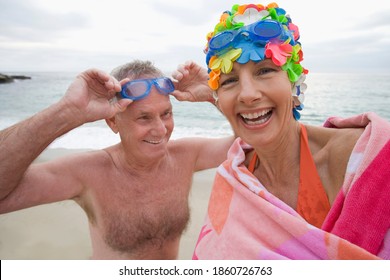 Smiling Portrait Of A Mature Woman In Swimming Costume And Cap By A Man With Goggles.