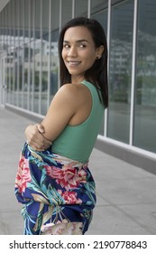 Smiling And Posing From Behind A Beautiful Latin Brunette Woman With Short Hair, Building Glass Background, Lifestyle Of Young Model In The Day