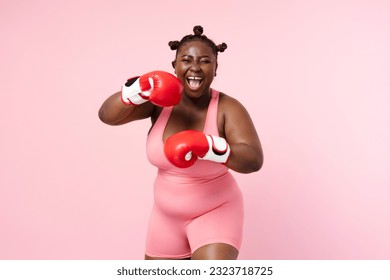 Smiling positive african american woman wearing sports uniform, red boxing gloves looking at camera isolated on pink background. Nigerian sportswoman training, health care, lifestyle - Powered by Shutterstock