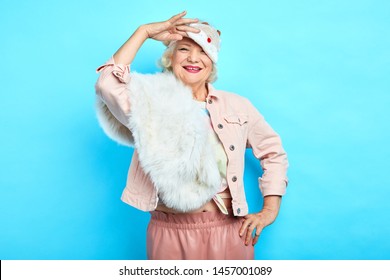 smiling positive fashion woman taking off, putting on mask,isolated blue background. studio shot.