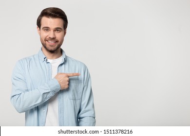 Smiling Positive Happy Male Client Pointing Finger Aside At Empty Free Copy Space For New Product Promo, Good Deal Offer, Education Or Career Opportunity, Isolated On Grey White Studio Background.