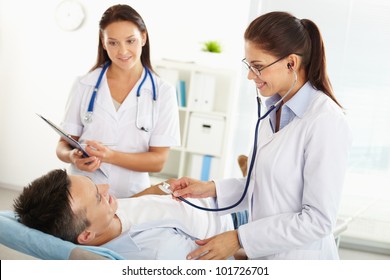 Smiling Practitioner Examining The Patient, Her Assistant Taking Notes