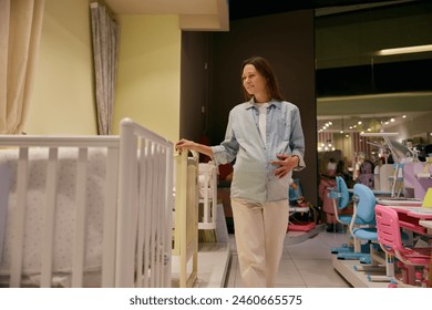 Smiling pregnant woman choosing baby crib at shopping mall - Powered by Shutterstock