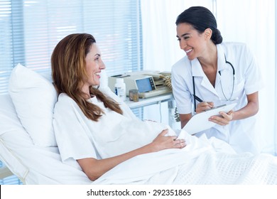 Smiling pregnant woman with her doctor in hospital room
