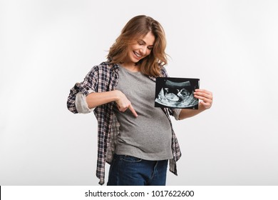 Smiling Pregnant Woman With Ultrasound Scan Pointing At Tummy Isolated On Grey