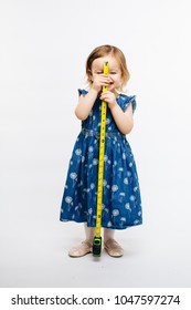 A smiling preschool girl holding a measuring tape in front of her, grow so fast