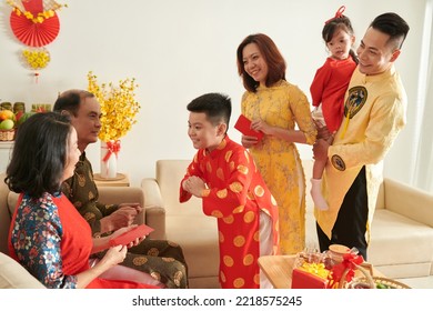 Smiling preteen boy greeting grandparents with bow when family visiting them fot Tet celebration - Shutterstock ID 2218575245