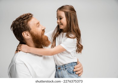 Smiling preteen girl hugging bearded dad isolated on grey - Powered by Shutterstock