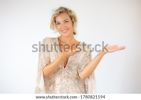 Smiling pretty blonde woman in a party dress gesturing on white background