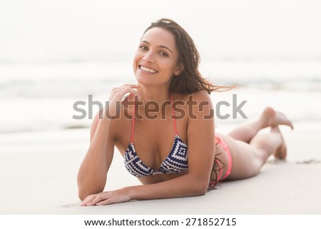 Smiling pretty brunette posing in bikini on the beach