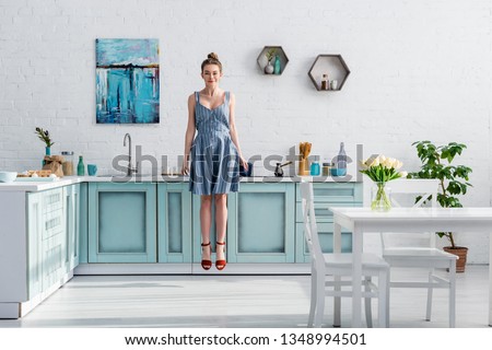 smiling pretty girl levitating in air in turquoise and white kitchen 