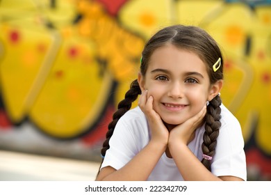 Smiling Pretty Little Girl with Braided Hair Putting Both Hands on Face, Looking at Camera