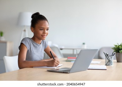 Smiling Pretty Smart Teen African American Girl Student Studying At Home, Watching Online Lesson On Laptop, Preparing For Test, Doing Homework With Laptop. Distance Modern Education And Knowledge