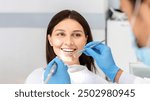 Smiling pretty woman looking with trust at dentist doctor during treatment