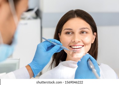 Smiling pretty woman looking with trust at dentist doctor during treatment