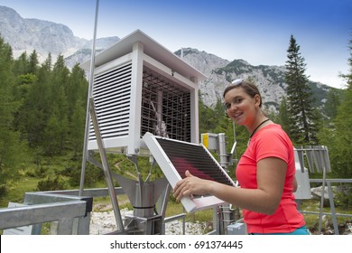 Smiling pretty woman meteorologist reading meteodata instruments in modern meteorologic observation station, high in mountains