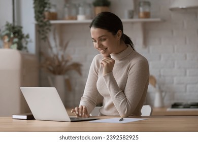Smiling pretty woman searching information on internet, working or studying, busy in self-education, ordering goods or food on-line using laptop. E-commerce client, modern wireless tech usage concept