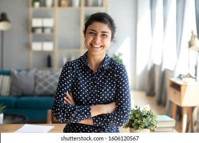 Smiling pretty young adult indian woman looking at camera posing at modern home arms crossed, cheerful happy ethnic girl student self employed lady laughing enjoying distance job education, portrait - Powered by Shutterstock