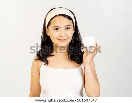 smiling pretty young girl holding a white cream beauty product with one hand