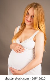 smiling pretty young pregnant blonde in white night-shirt isolated