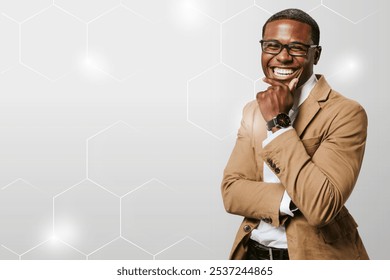 Smiling professional African American man in glasses and a brown blazer, standing confidently with a hand on his chin. Hexagonal pattern background adds a modern touch to confident business image. - Powered by Shutterstock